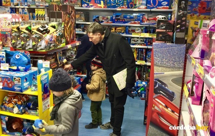 Un padre ayuda a sus hijos a escoger los juguetes