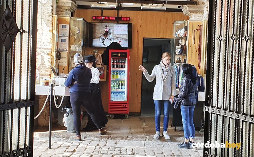 Dos empleadas de Caballerizas indicando a dos turistas que hay que pagar 5 euros de entrada
