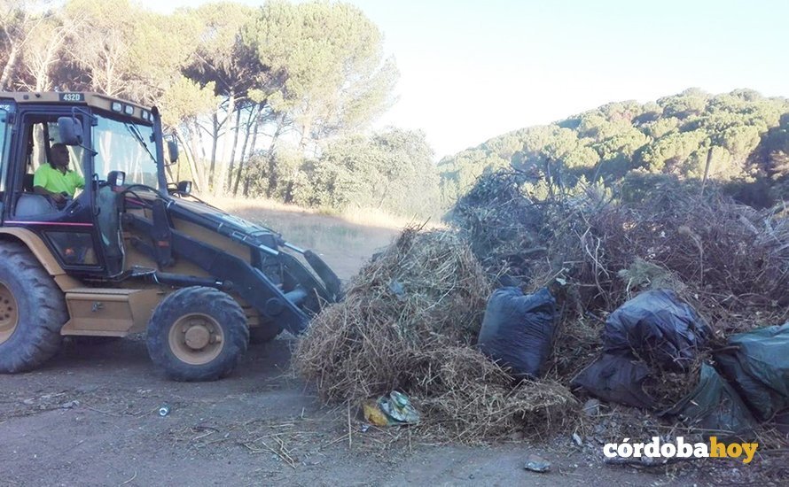 Una pala mecánica enviada por Sadeco a limpiar de basura un paraje en Trassierra en julio de 2020
