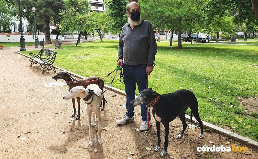 Un hombre con sus tres galgos en un parque de Córdoba
