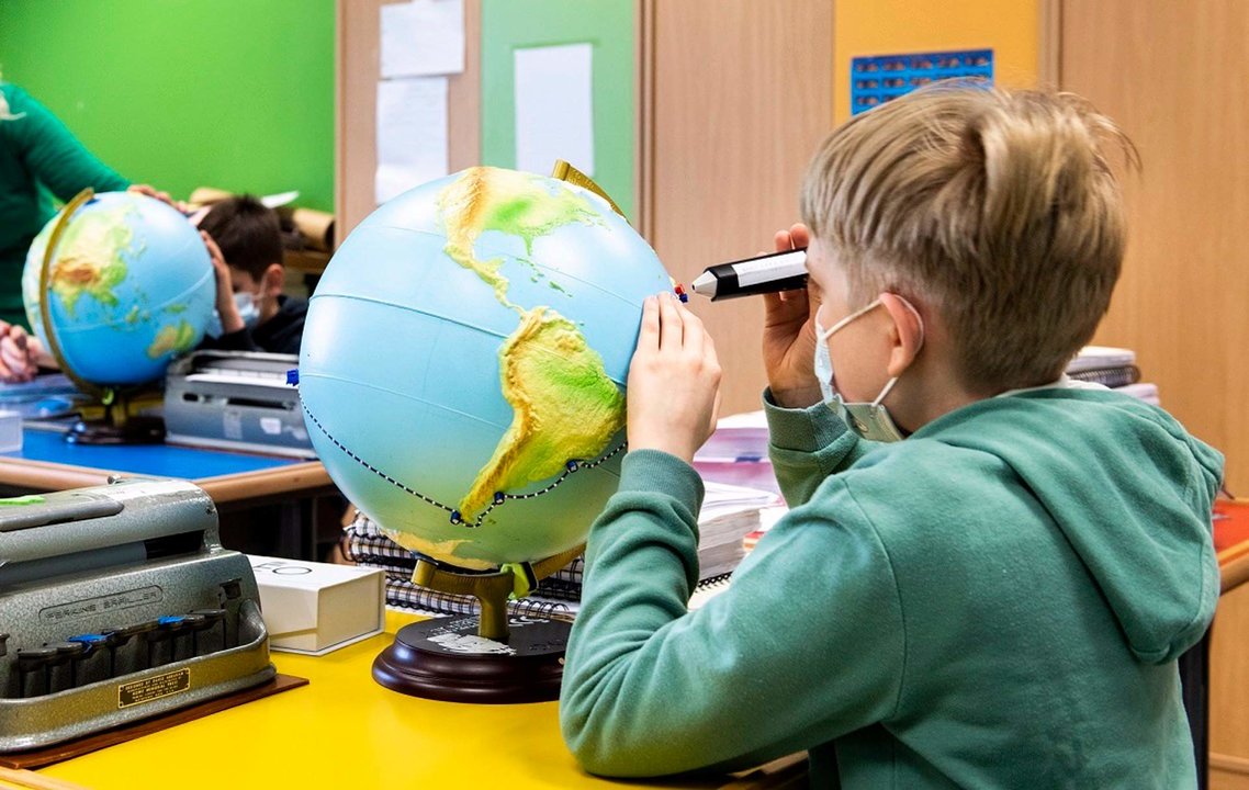 Un alumno de primaria utiliza un globo terraqueo adaptado con relieve