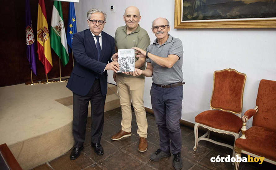 Salvador Fuentes (izda.) muestra el libro ‘Ni héroes ni soldados, fotoperiodistas’, del fotógrafo Antonio Jesús González (centro)