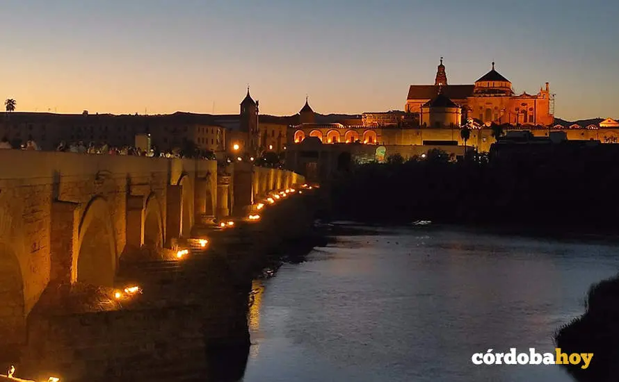 Turistas cruzan el Guadalquivir por el Puente Romano de C&oacute;rdoba, con la Puerta del Puente y la Mezquita-Catedral al fondo, en una imagen de archivo