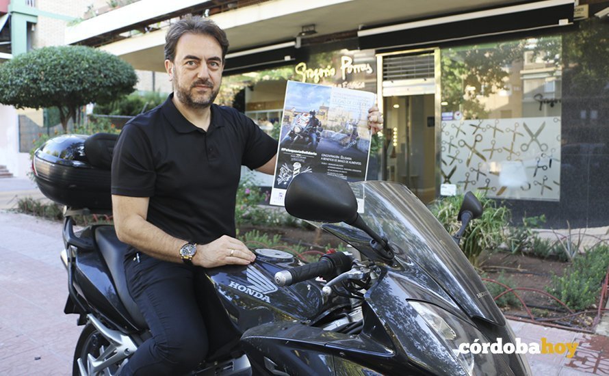 Gregorio Porras sobre su moto y con el cartel de la concentración de peluqueros moteros delante de su establecimeinto en la calle El Nogal