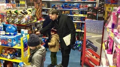 Un padre ayuda a sus hijos a escoger los juguetes