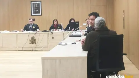 La rea, de espaldas, en el banquillo de los acusados