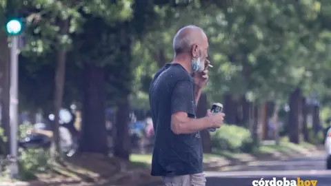 Un hombre fuma apart&aacute;ndose la mascarilla