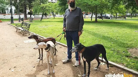 Un hombre con sus tres galgos en un parque de C&oacute;rdoba