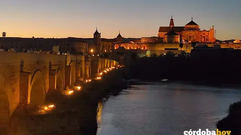 Turistas cruzan el Guadalquivir por el Puente Romano de C&oacute;rdoba, con la Puerta del Puente y la Mezquita-Catedral al fondo, en una imagen de archivo