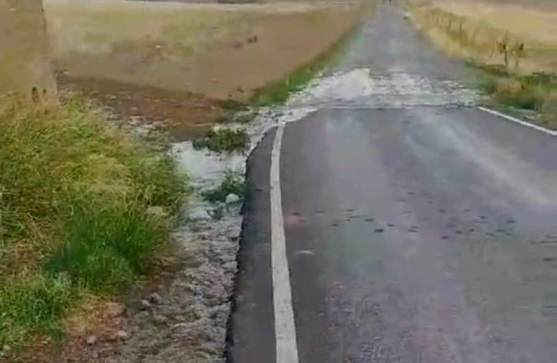 Rotura en el depósito en Peñarroya por el que se vierte agua, que llega a la carretera de acceso